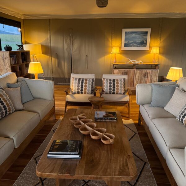 Lounge area at Little Enkewa Camp with cozy sofas and warm lighting in the Masai Mara