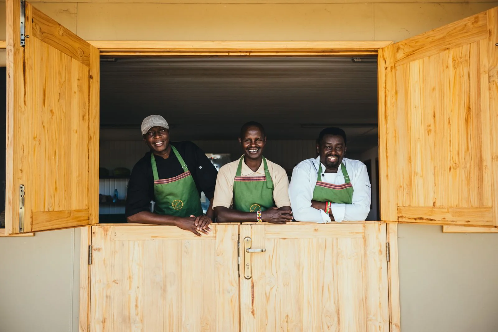 Little Enkewa kitchen team smiling at the kitchen window