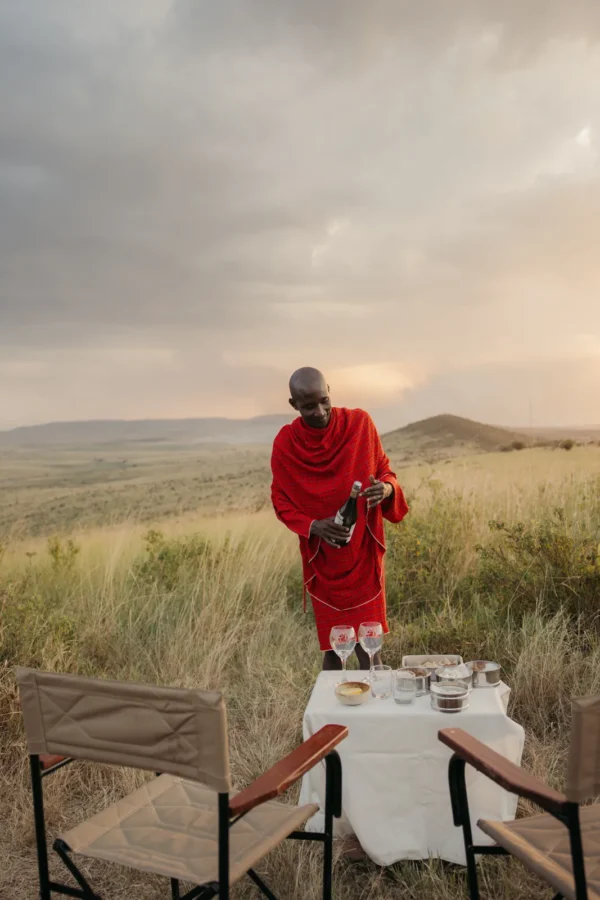 Maasai guide preparing sundowners on the savannah at sunset